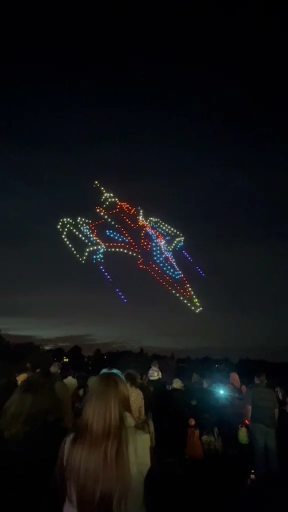 A red, white and blue spaceship drawn in drone lights over the night sky above Dunorlan Park